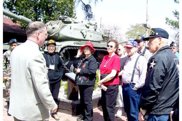 Second Infantry Division Museum Director William Michale Alexander, left, greets visiting Korean War veterans and family members Thursday at Camp Red Cloud, South Korea.