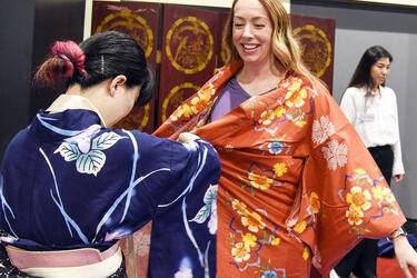 A Japanese service member helps Maj. Michelle Binder wear a yukata during a cultural exchange at the USO on Yokota Air Base, Japan, July 22, 2023. 