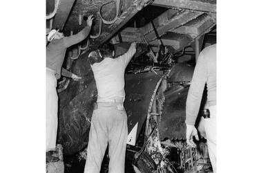 Crew members examine the crushed remains of the Banshee jet