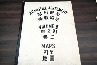 A large booklet that says “Armistice Agreement Maps Volume II” on the cover in black lettering and translated into Chinese and Korean.
