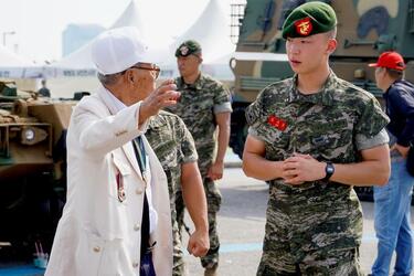 A U.S. Marine veteran shakes hands with a South Korean marine veteran at a ceremony.