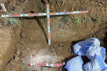An unexploded bomb is seen being uncovered in the dirt.