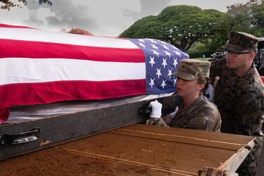 A transfer case containing Korean War remains is loaded into a truck.