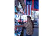 A cashier at a gas station in southern Guam waits on customers, while the Guam and U.S. flags hang in the window.