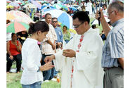 Marissa Laracuente, 11, receives Holy Communion from Father Carl Vila during the All Souls Day Mass on Wednesday in the Guam Veterans Cemetery.