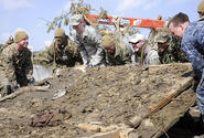 Army veteran Matt Szymanski, fifth from left with the U.S. flag patch on his hat, helps a group of Marines, airmen and sailors attempt to lift a giant piece of debris while helping clean Noda Village, about a two-hour drive from Misawa Air Base, Japan, during a March 29 trip.