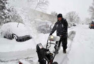 Air Force Master Sgt. Greg Pocaigue uses a snowblower to dig out his car.