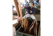 Customer Shinobu Sashida helps load a compactor that scrunches cardboard boxes into 1,100-pound recyclable bales.