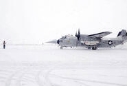 A sailor from Naval Air Facility Misawa - on Misawa Air Base, Japan - guides a C-2 passenger plane onto the ramp to disembark personnel during a heavy snow storm Saturday mor