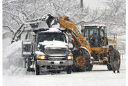 Workers move thousands of pounds of snow into one of a line of dumptrucks in the parking lot of the Army and Air Force Exchange store at Misawa Wednesday morning.