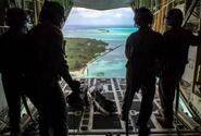 Loadmasters with the 36th Airlift Squadron out of Yokota Air Base, Japan, watch bundles parachute down to Nomwin, Federated States of Micronesia, Dec. 13, 2019, during the annual Operation Christmas Drop.